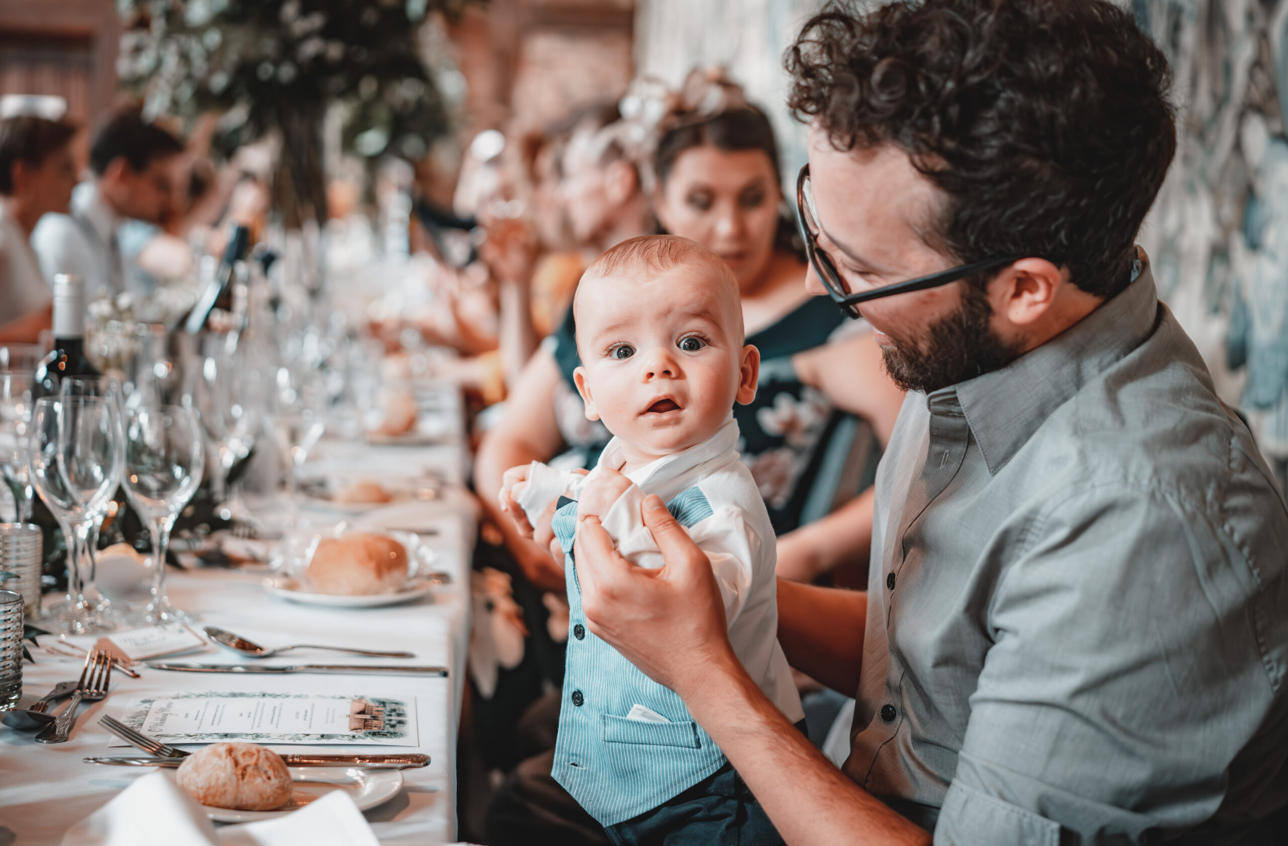 A baby is sitting at a table at a fairytale wedding reception, captured in enchanting wedding photography. (listing)