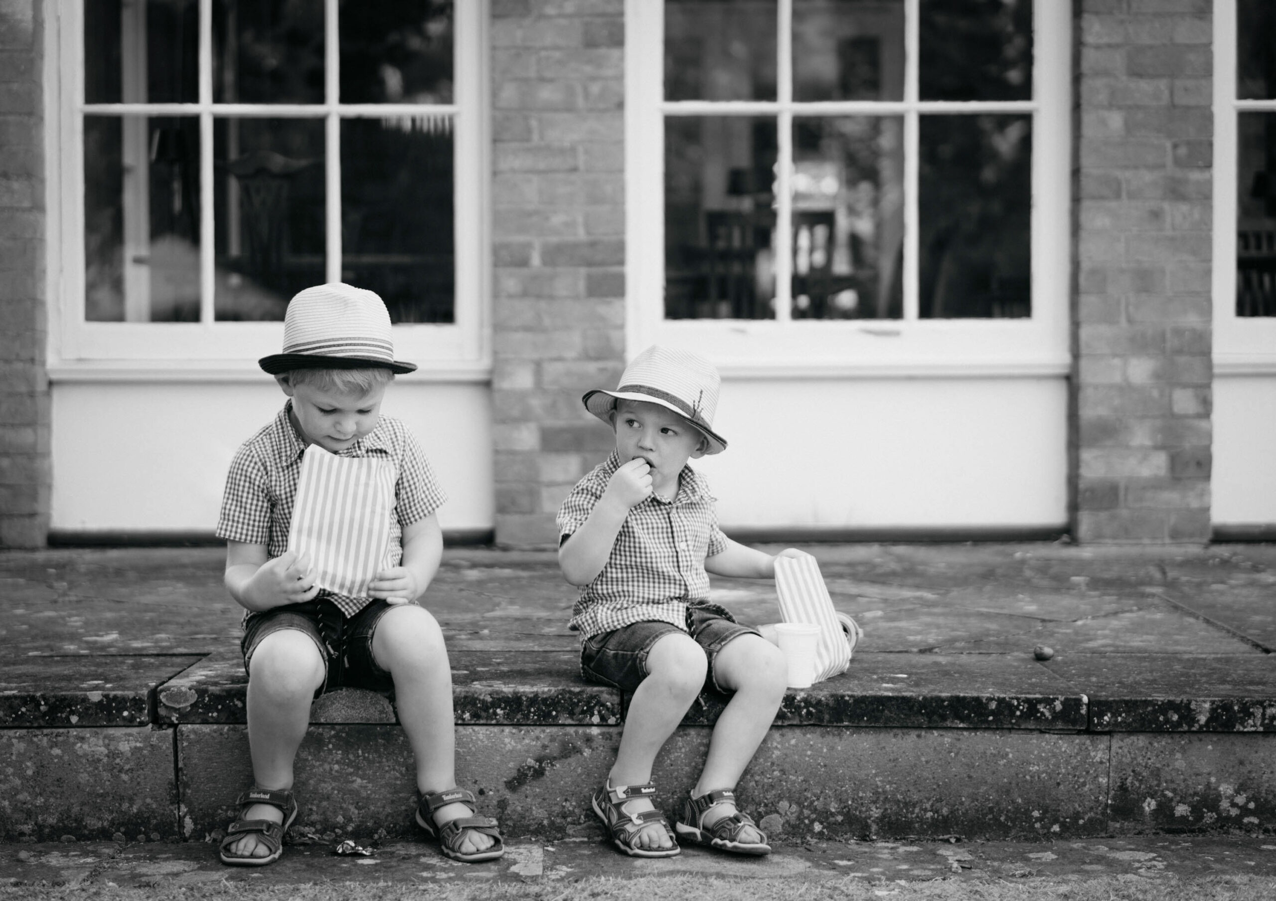 Two boys in hats sitting on the steps of a fairytale building. (listing)