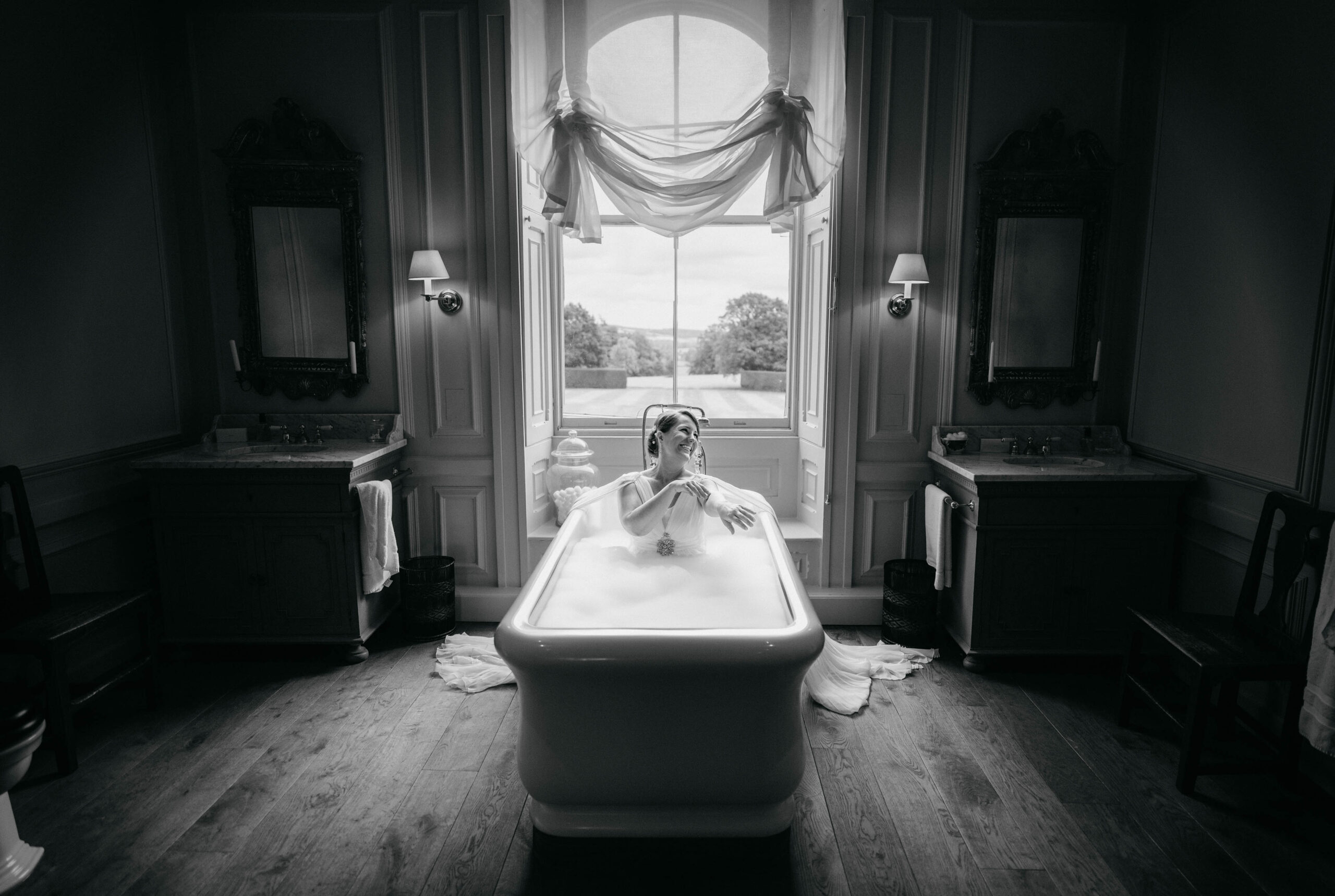 A bride is sitting in a fairytale bathtub in front of a window. (listing)