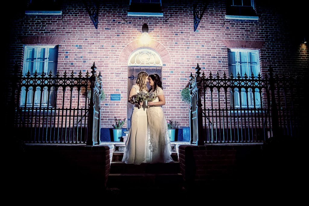 Wedding photographer duo capturing two brides at night. (listing)