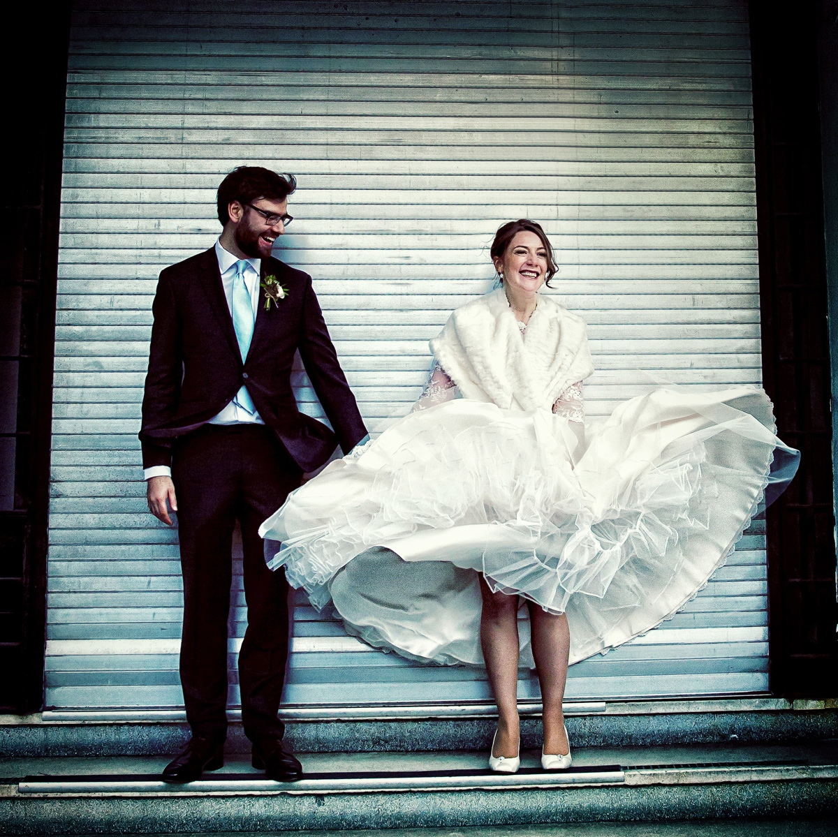 A wedding photographer duo capturing a bride and groom posing in front of a door. (listing)