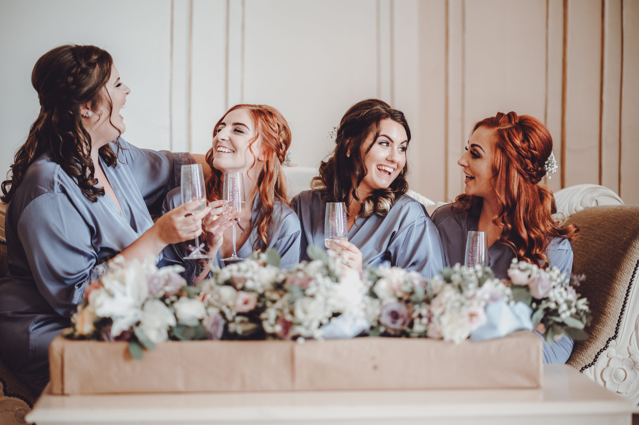 Four bridesmaids laughing on a couch. (listing)