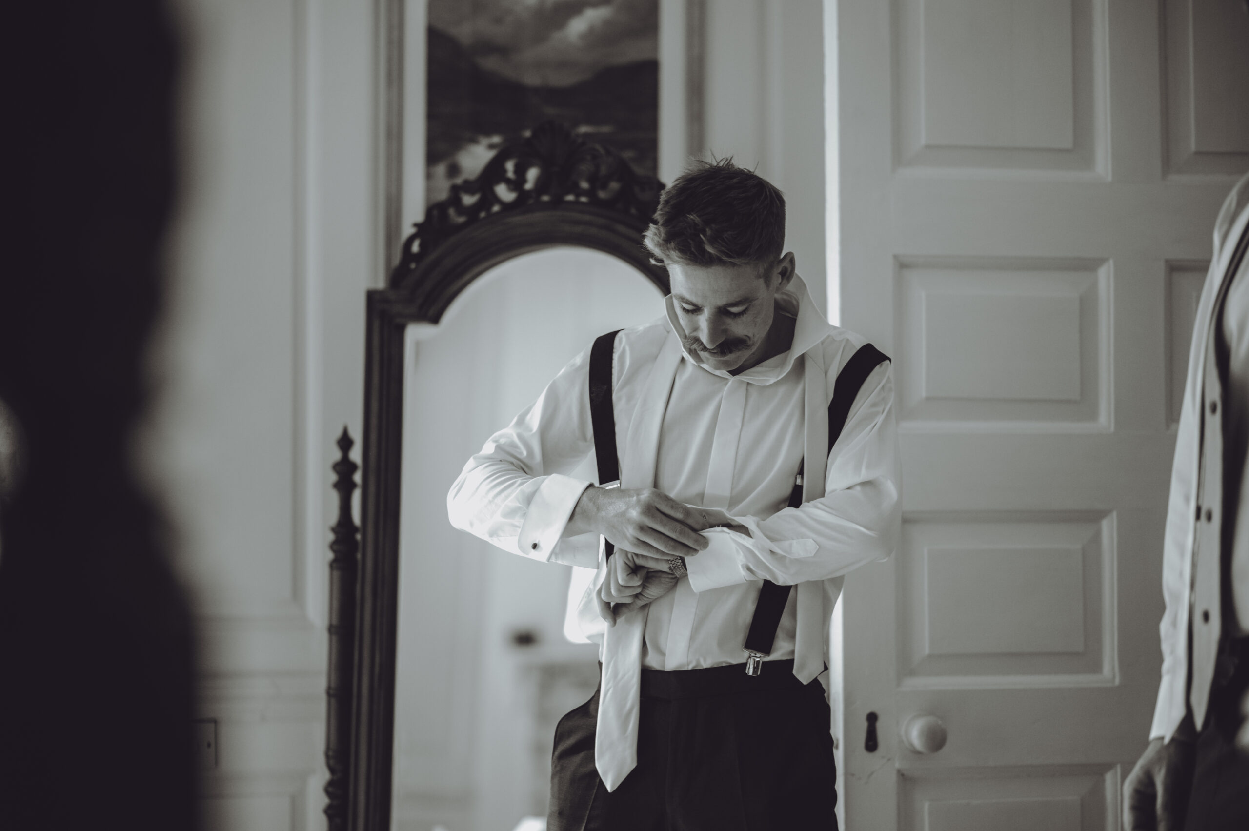A man is adjusting his tie in front of a mirror. (listing)