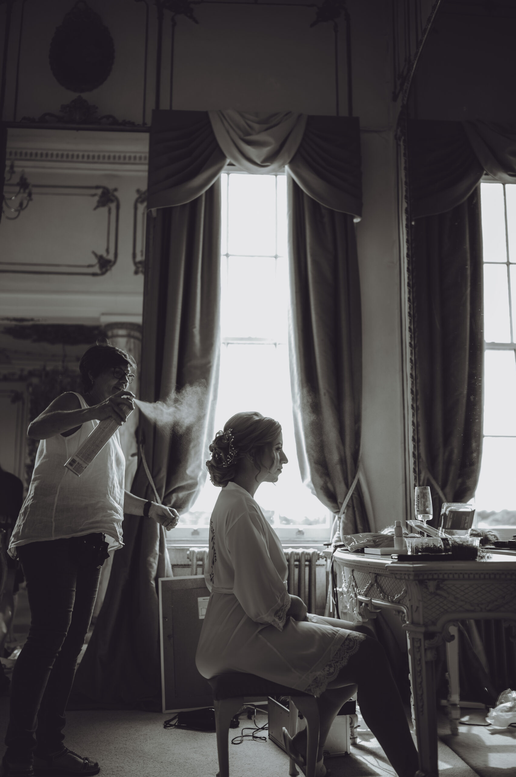 A bride getting ready in front of a mirror in a room. (listing)