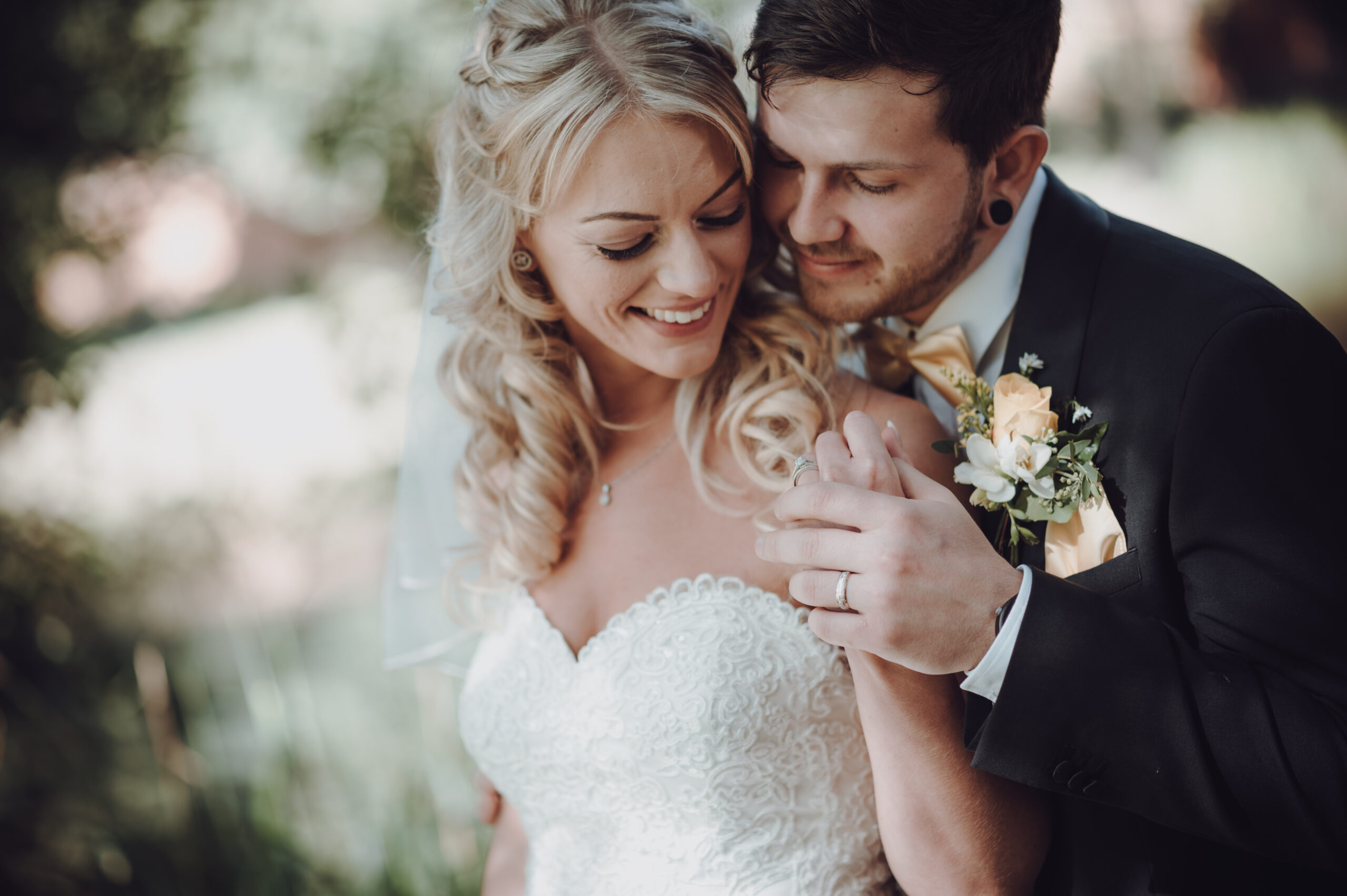A bride and groom embracing each other in the woods. (listing)