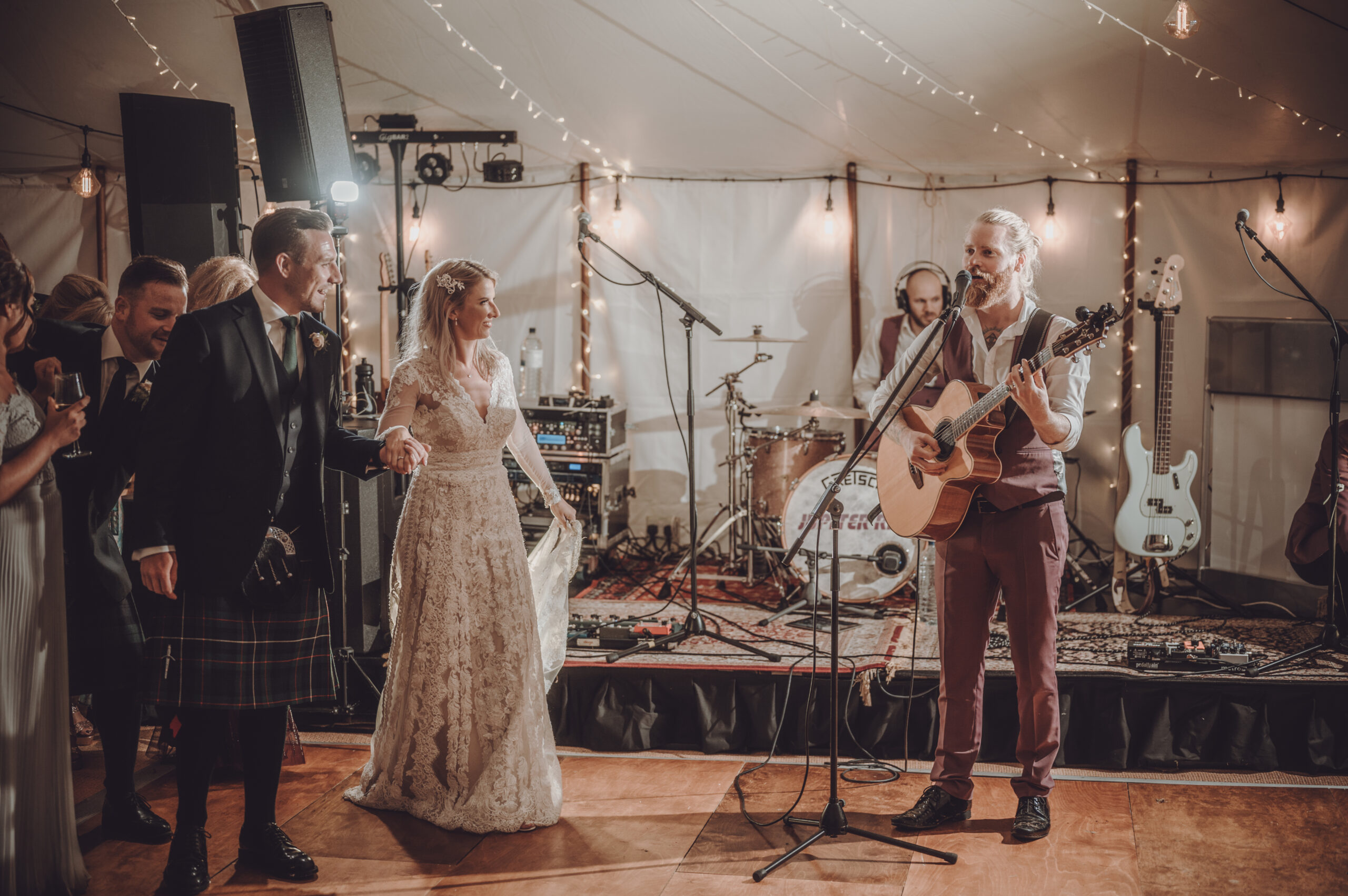 A bride and groom singing at a wedding reception in a tent. (listing)