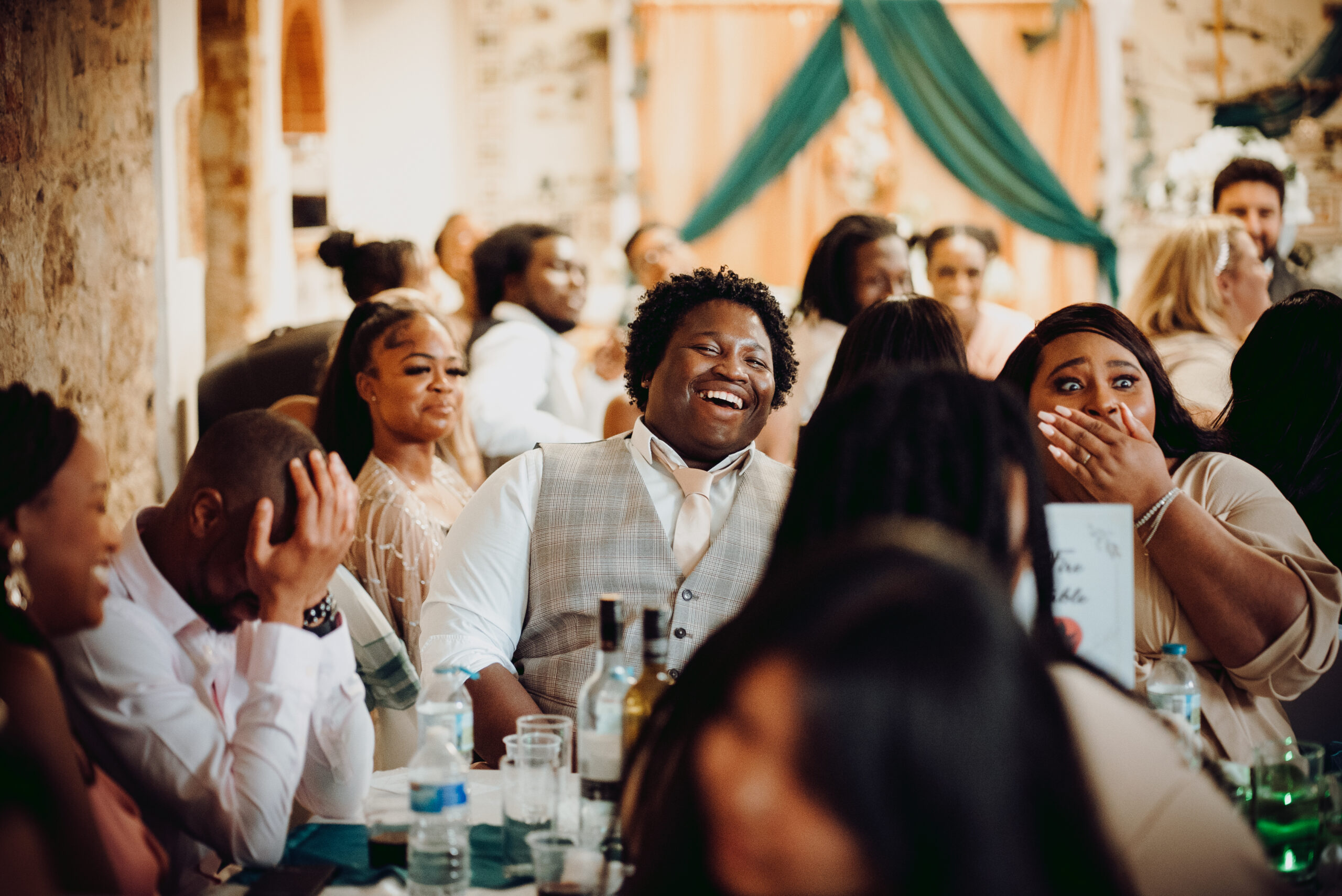 A group of people laughing at a wedding reception. (listing)