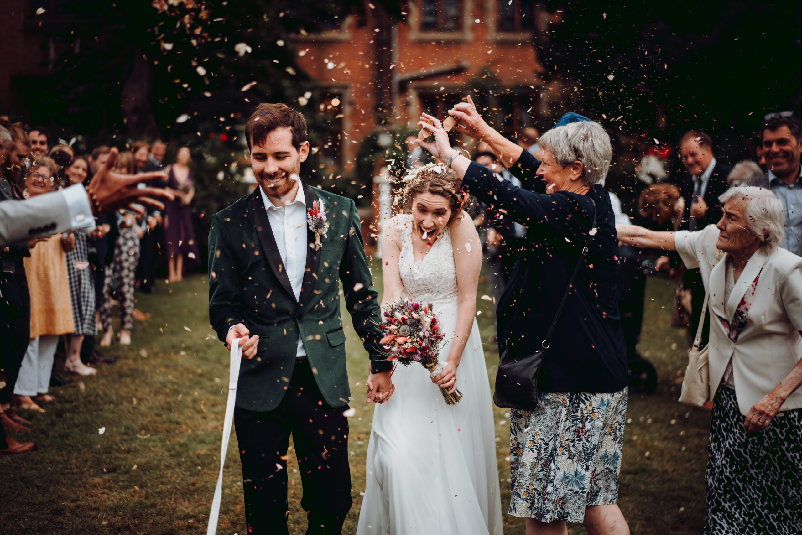 A bride and groom walking down the aisle with confetti thrown at them. (listing)