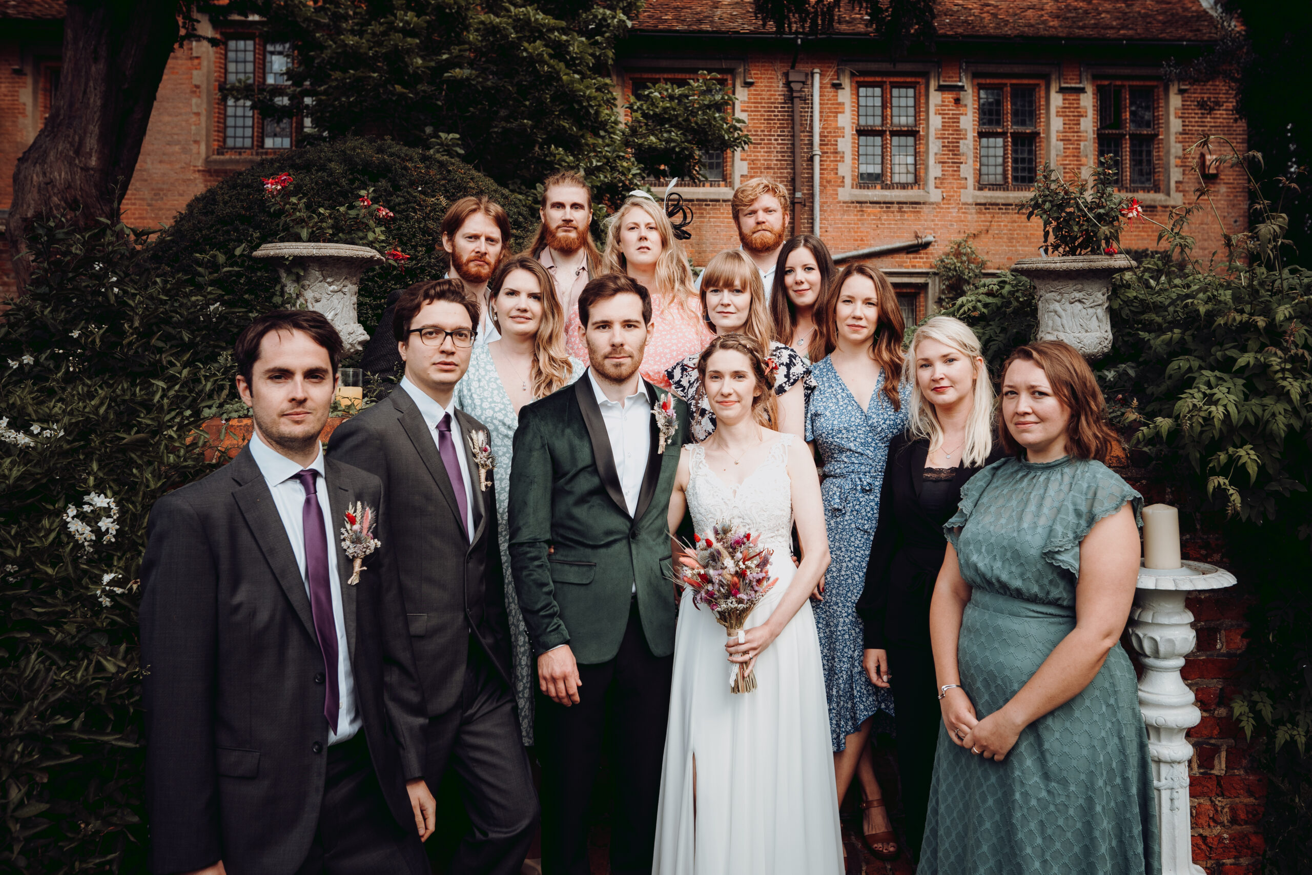 A wedding party posing in front of a house. (listing)
