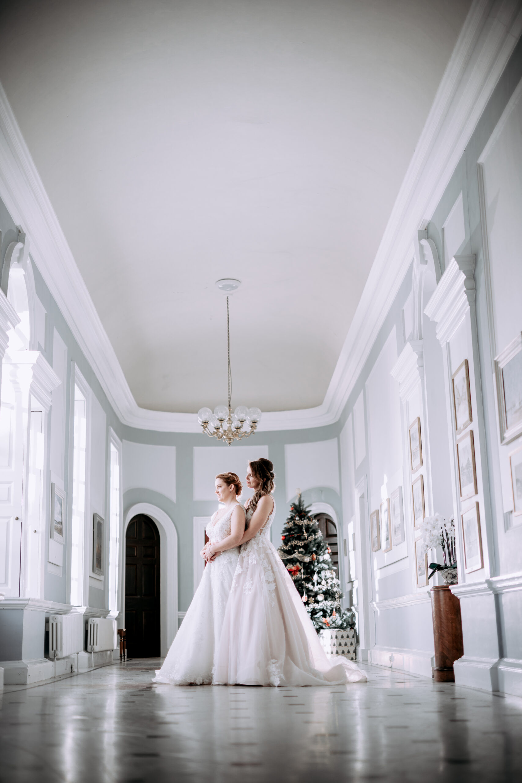 Two brides posing in a large hall. (listing)