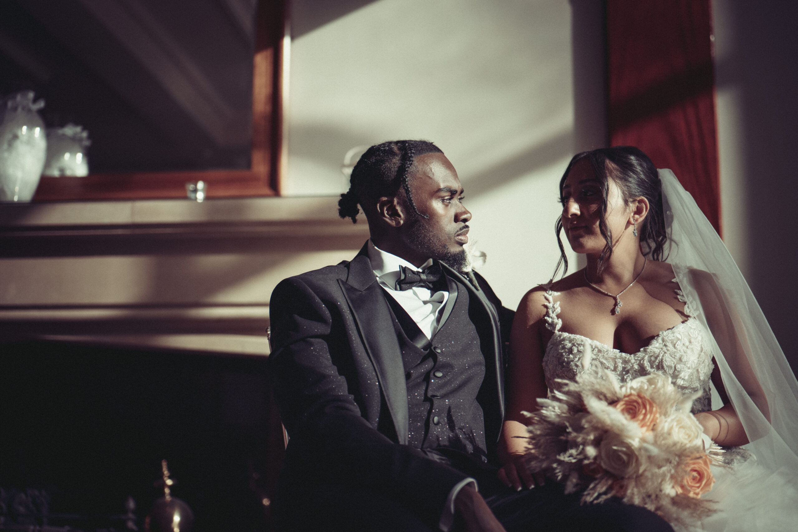 A bride and groom sitting in front of a fireplace. (listing)