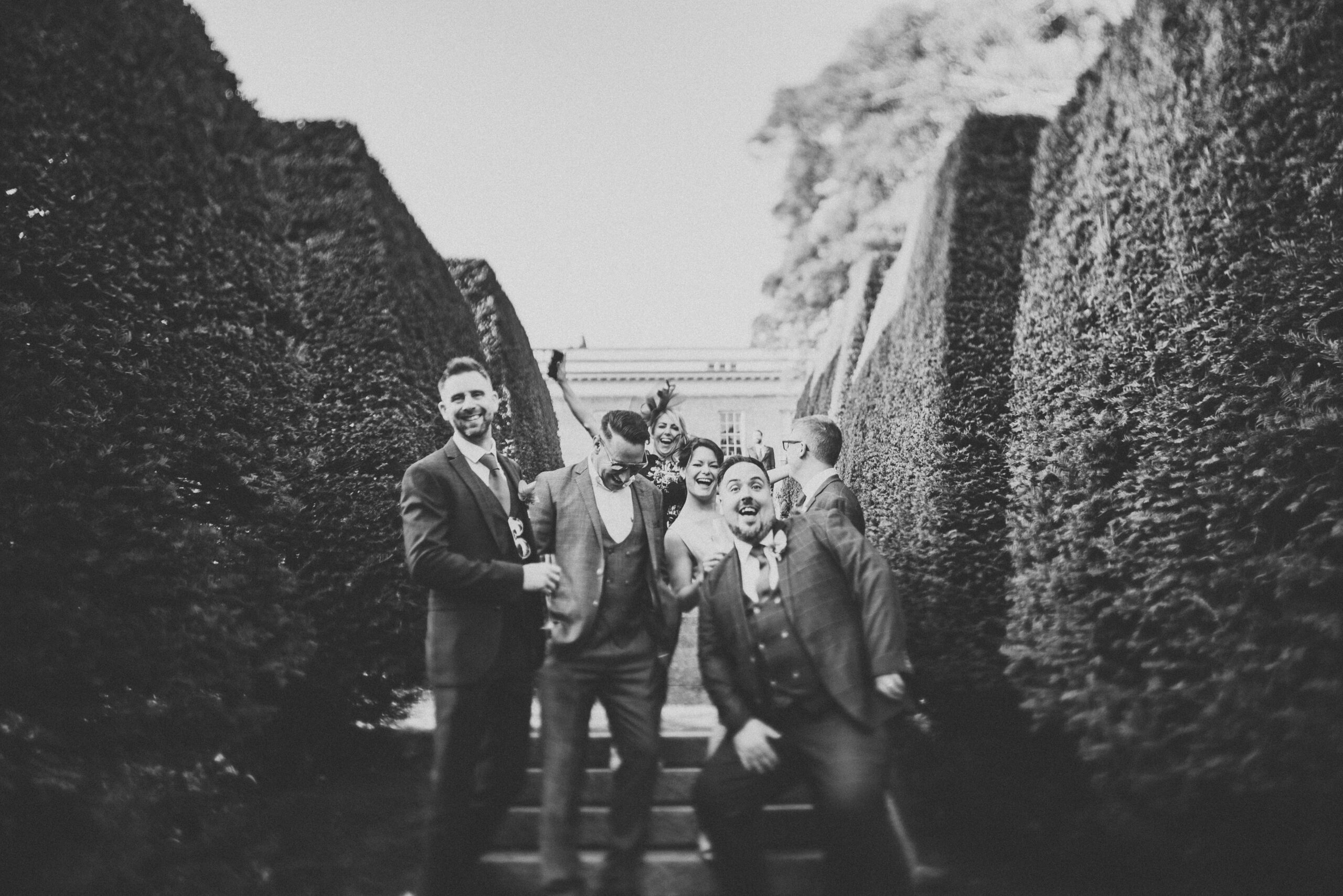 A black and white photo of a group of groomsmen and bridesmaids. (listing)