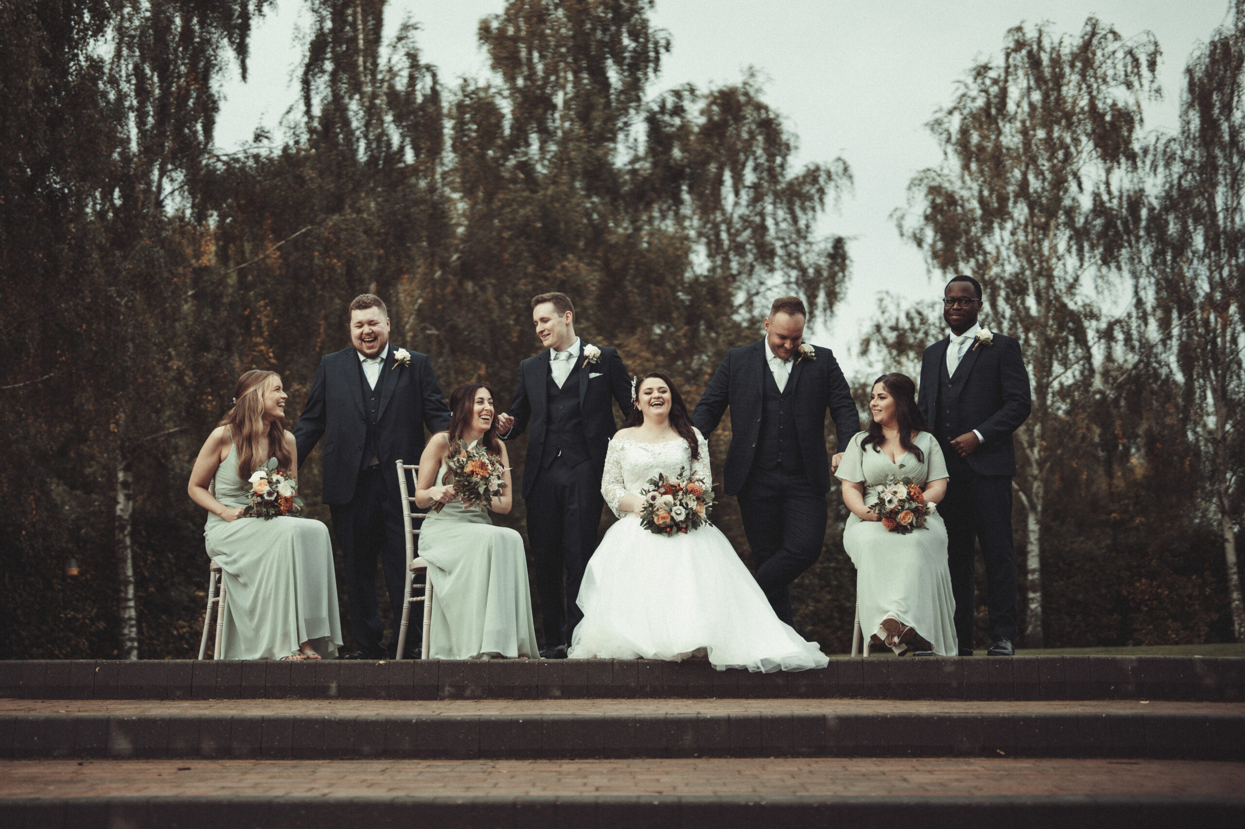 A group of bridesmaids and groomsmen posing for a photo. (listing)
