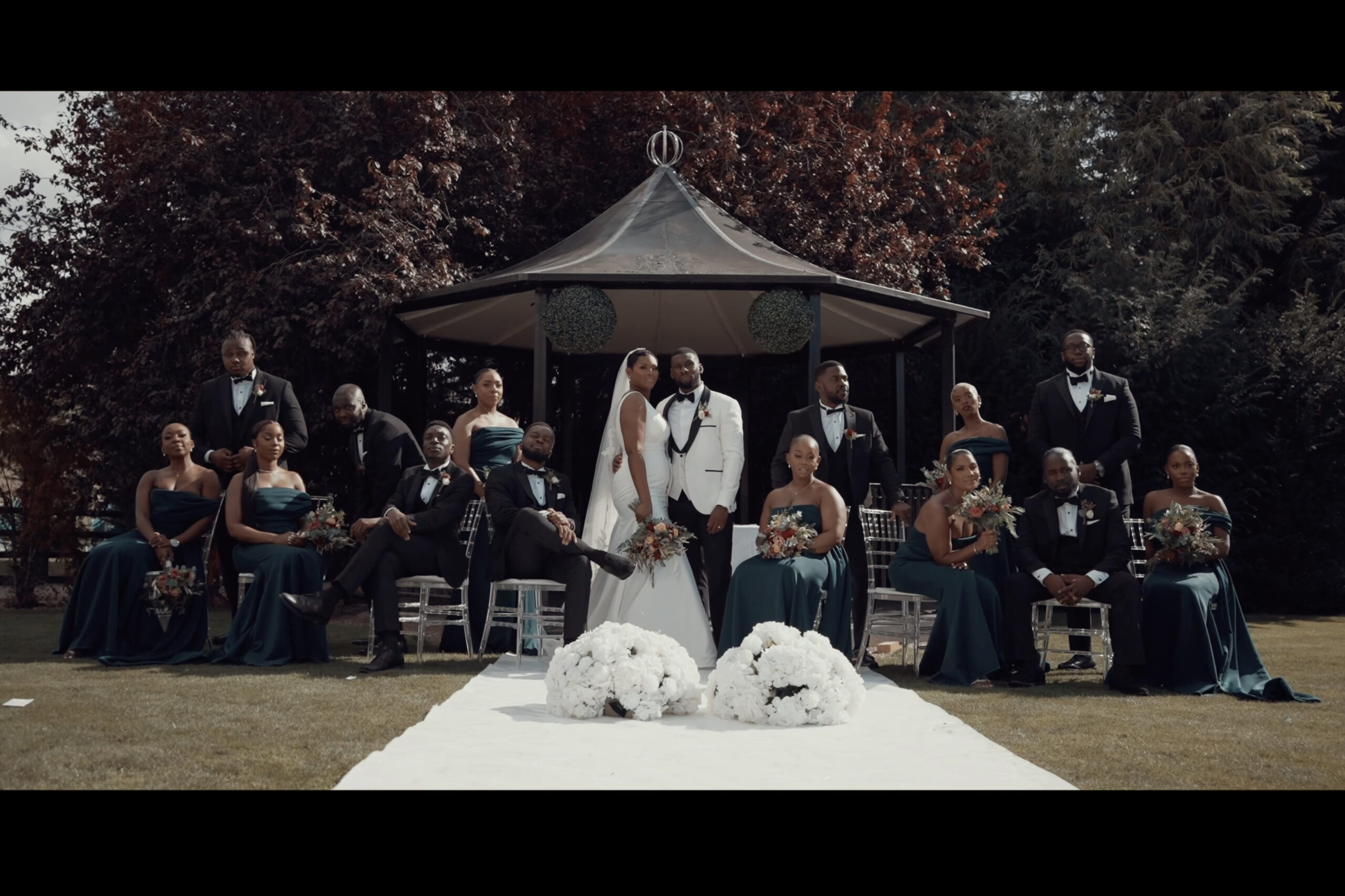 A wedding party posing in front of a gazebo. (listing)