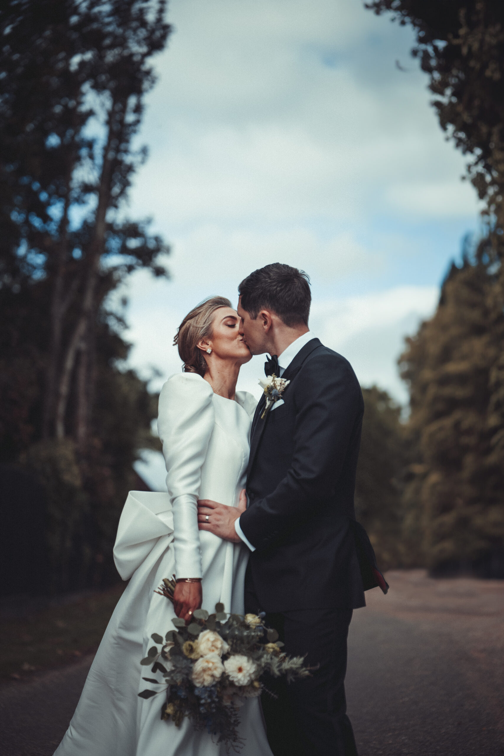 A bride and groom kissing in the woods. (listing)