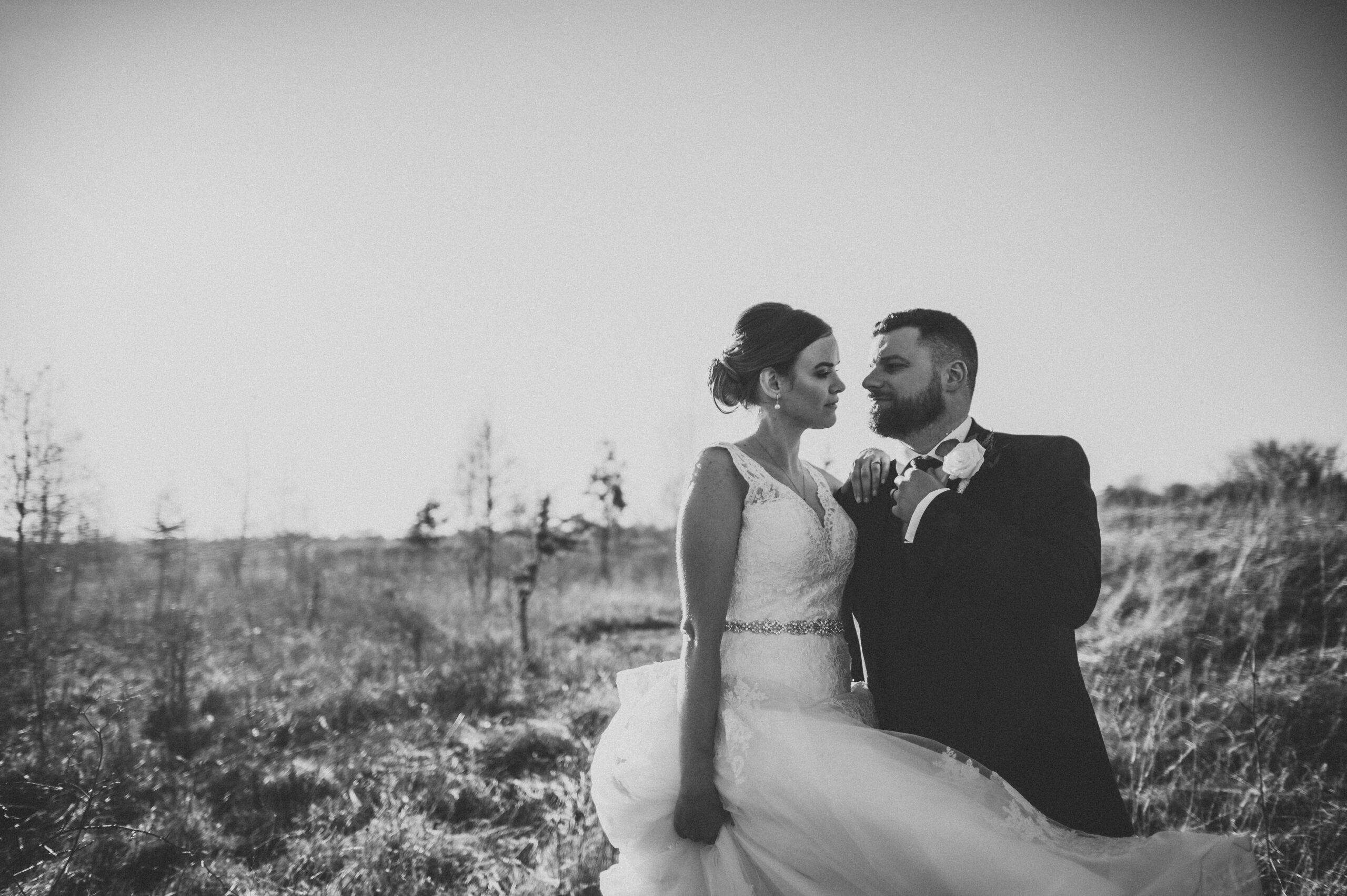 A bride and groom standing in a field. (listing)