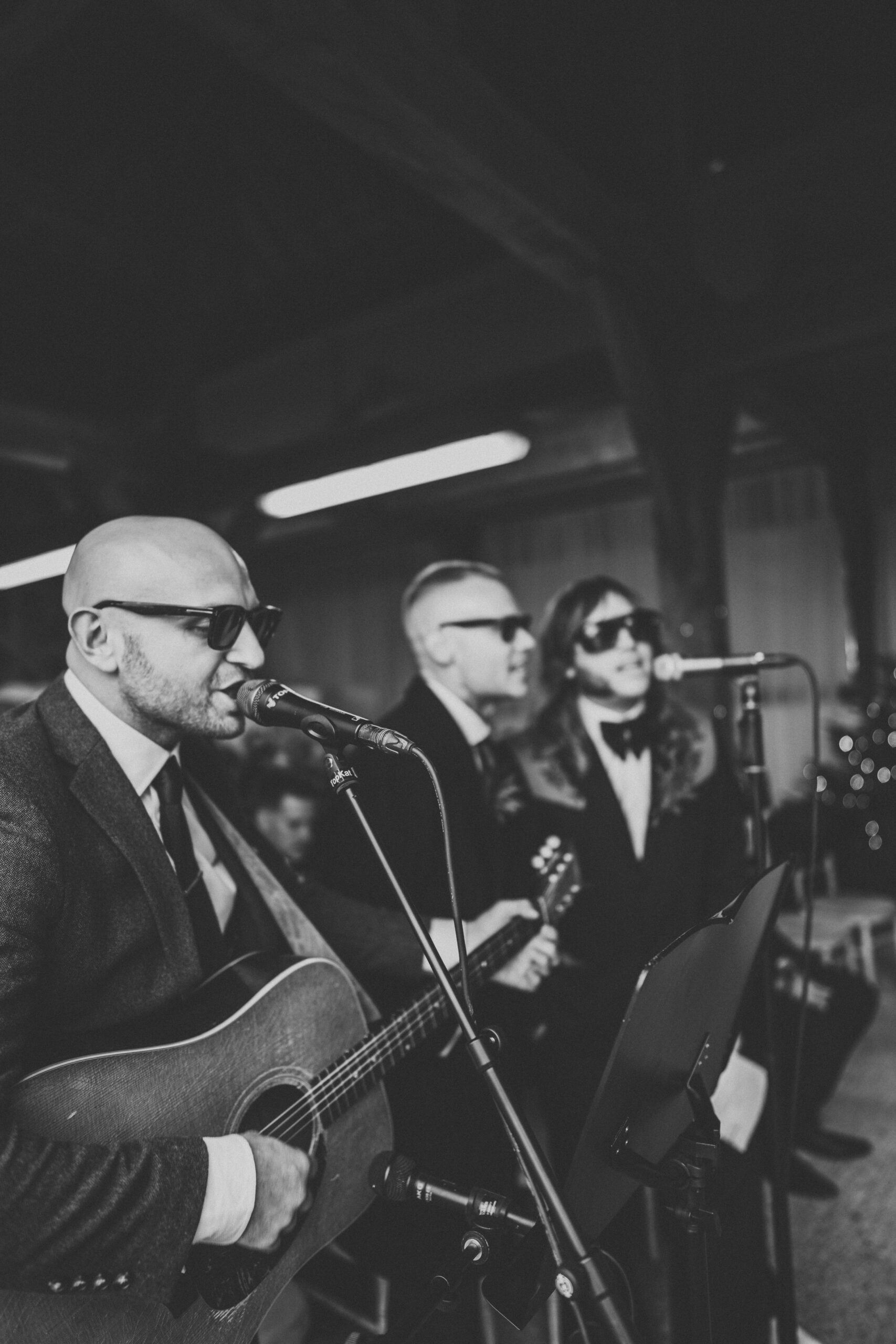 A black and white photo of a man in a suit playing an acoustic guitar. (listing)