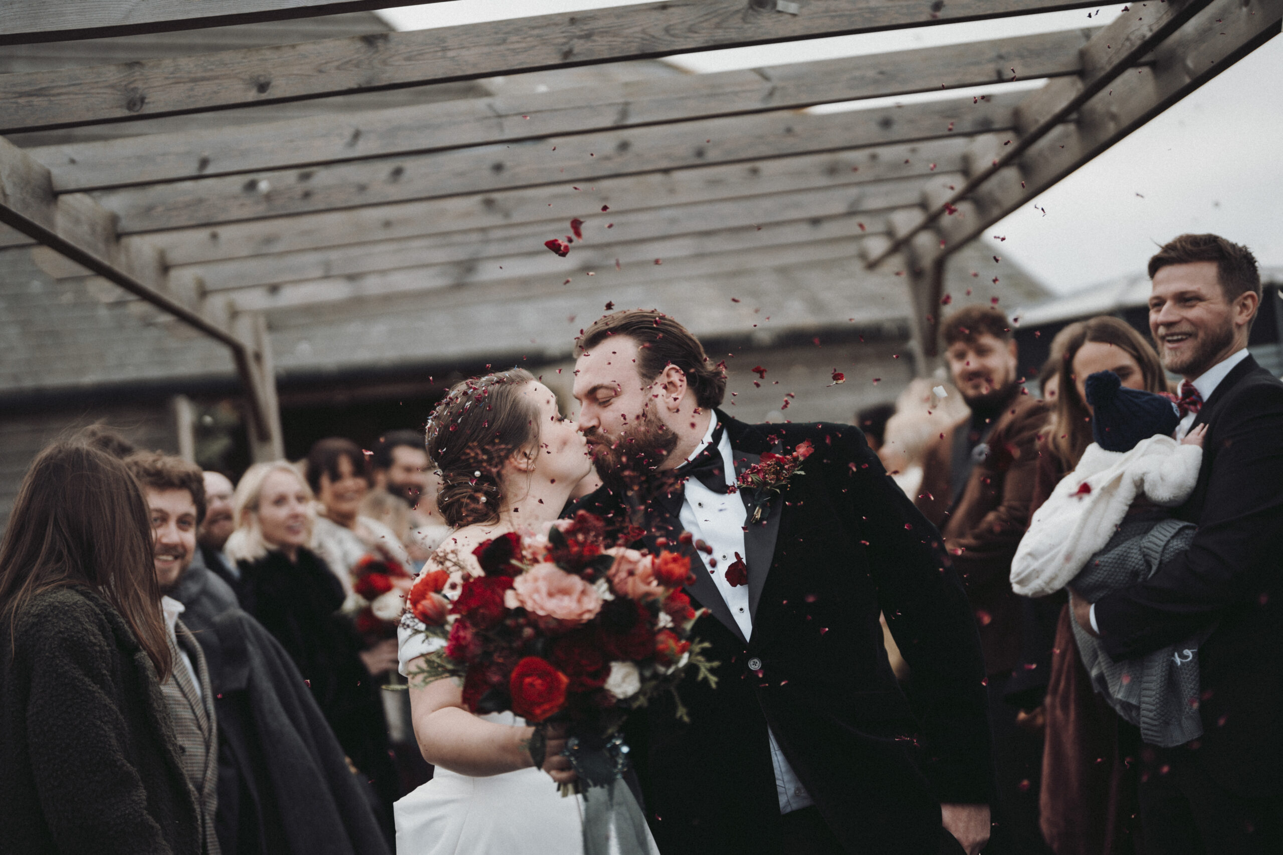 A bride and groom kissing under a pergola. (listing)