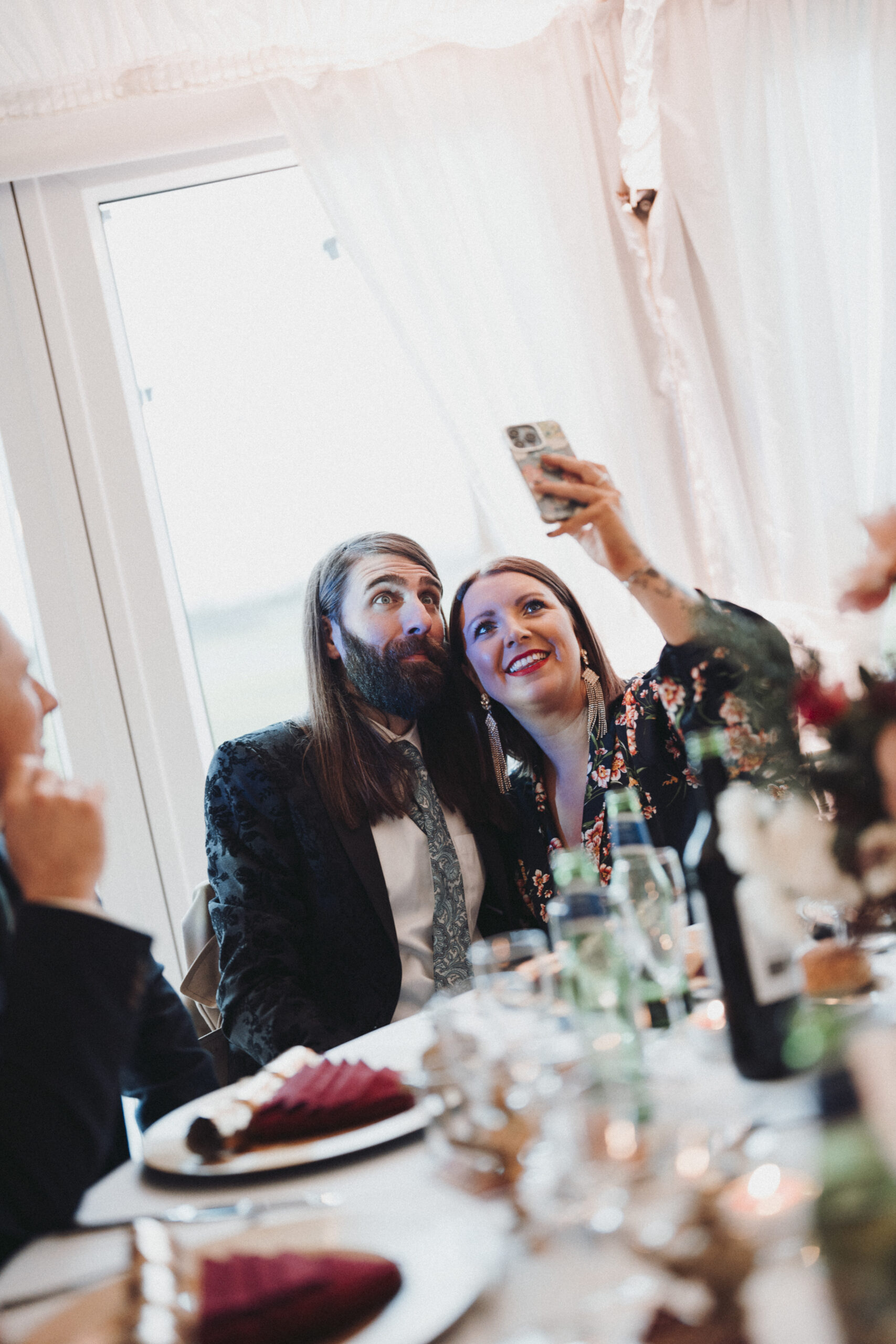 A man and woman taking a selfie at a table. (listing)