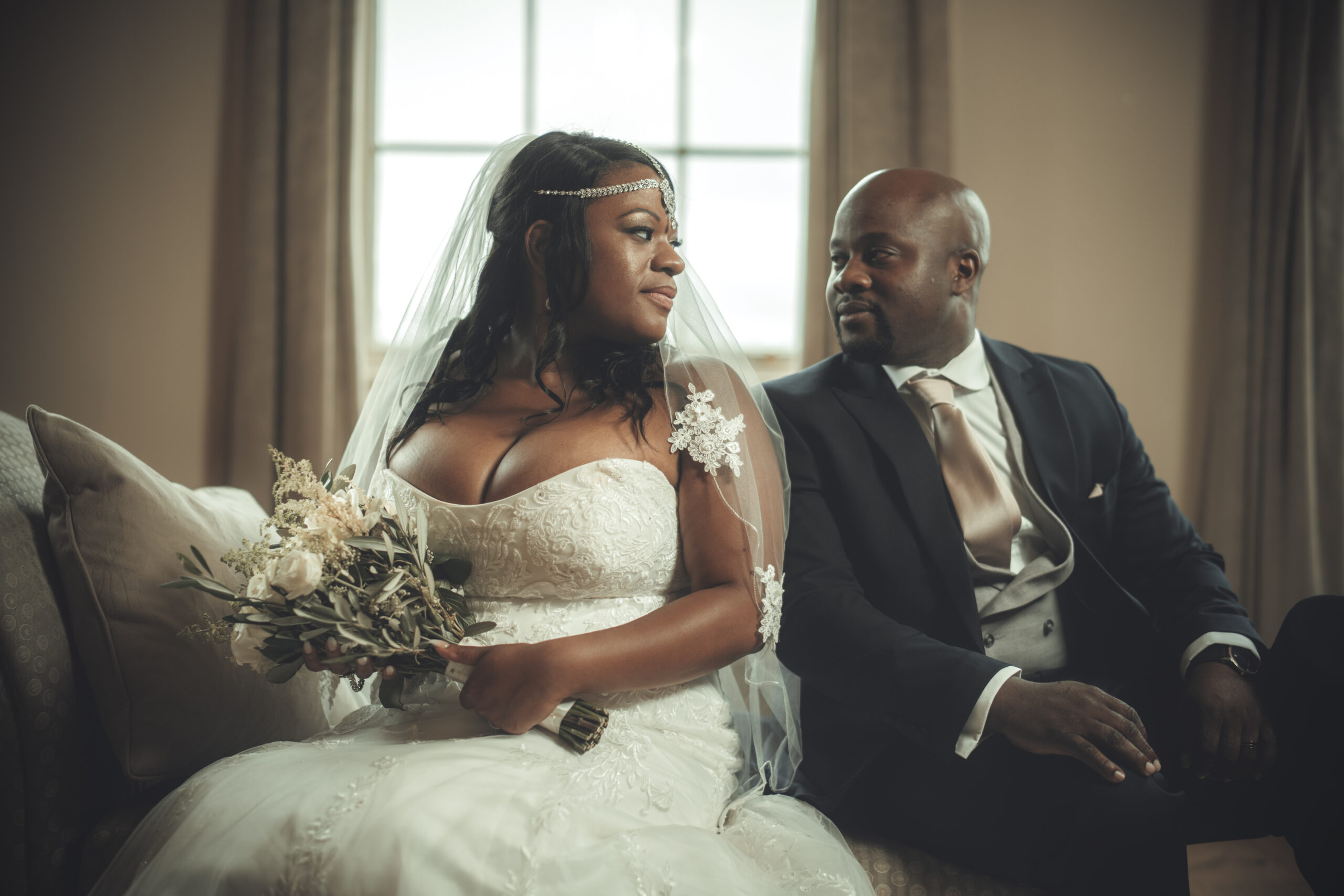 A bride and groom sitting on a couch. (listing)