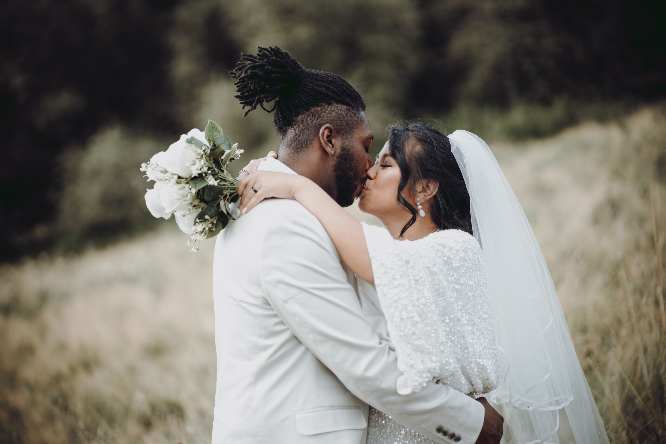 A bride and groom kissing in a field. (listing)