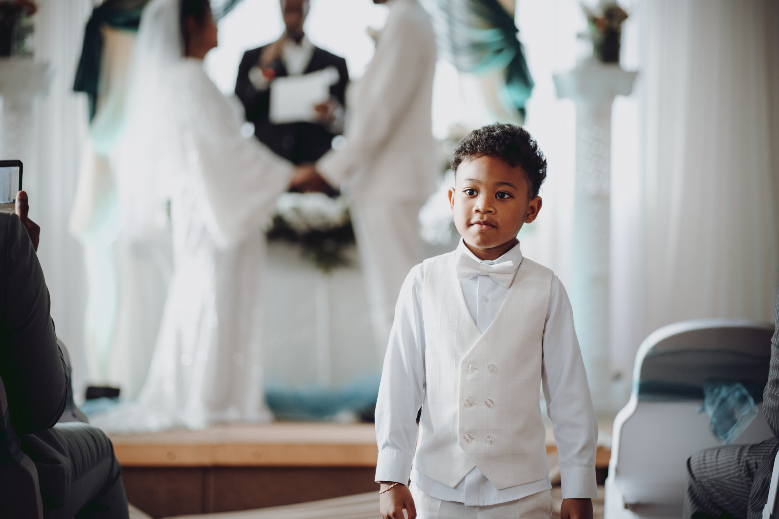 A young boy standing in front of a wedding ceremony. (listing)