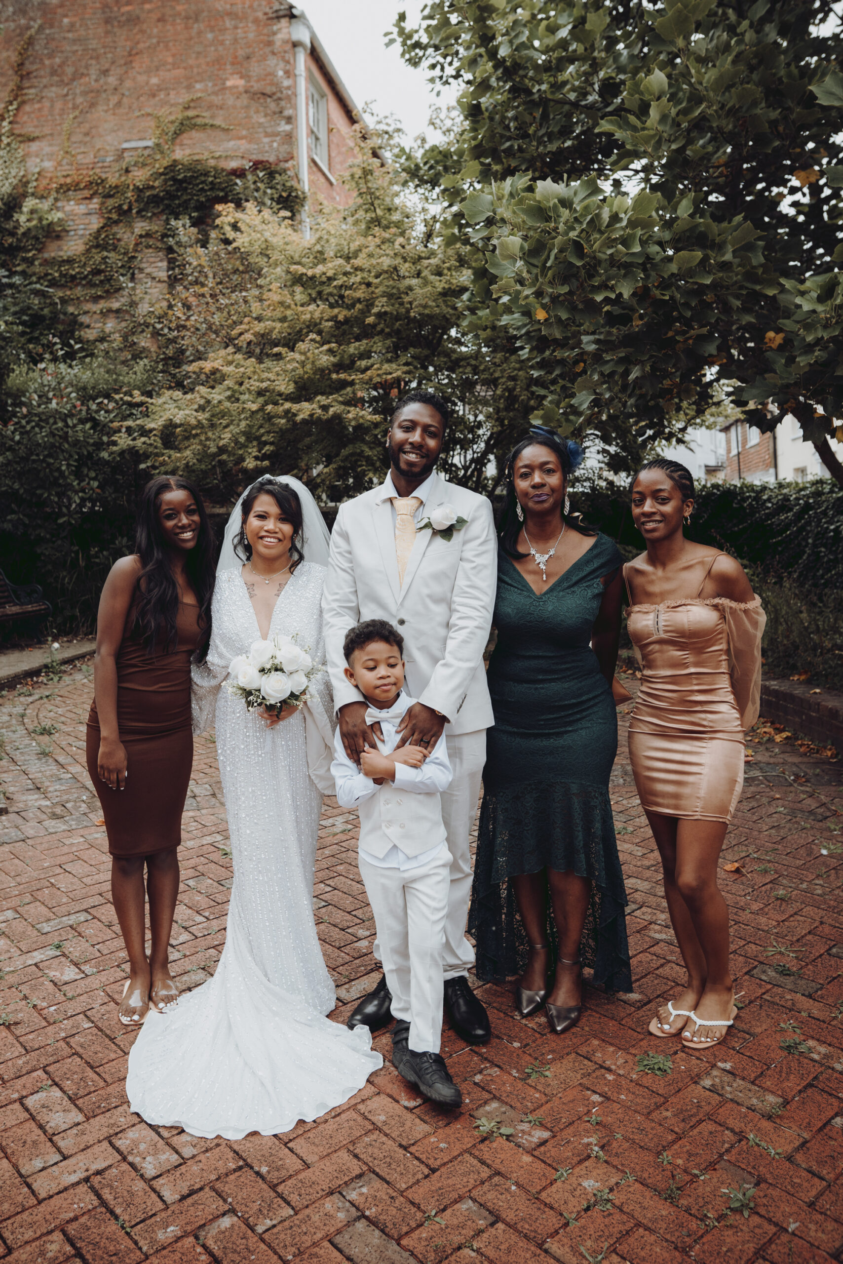 A bride and groom pose for a photo with their wedding party. (listing)