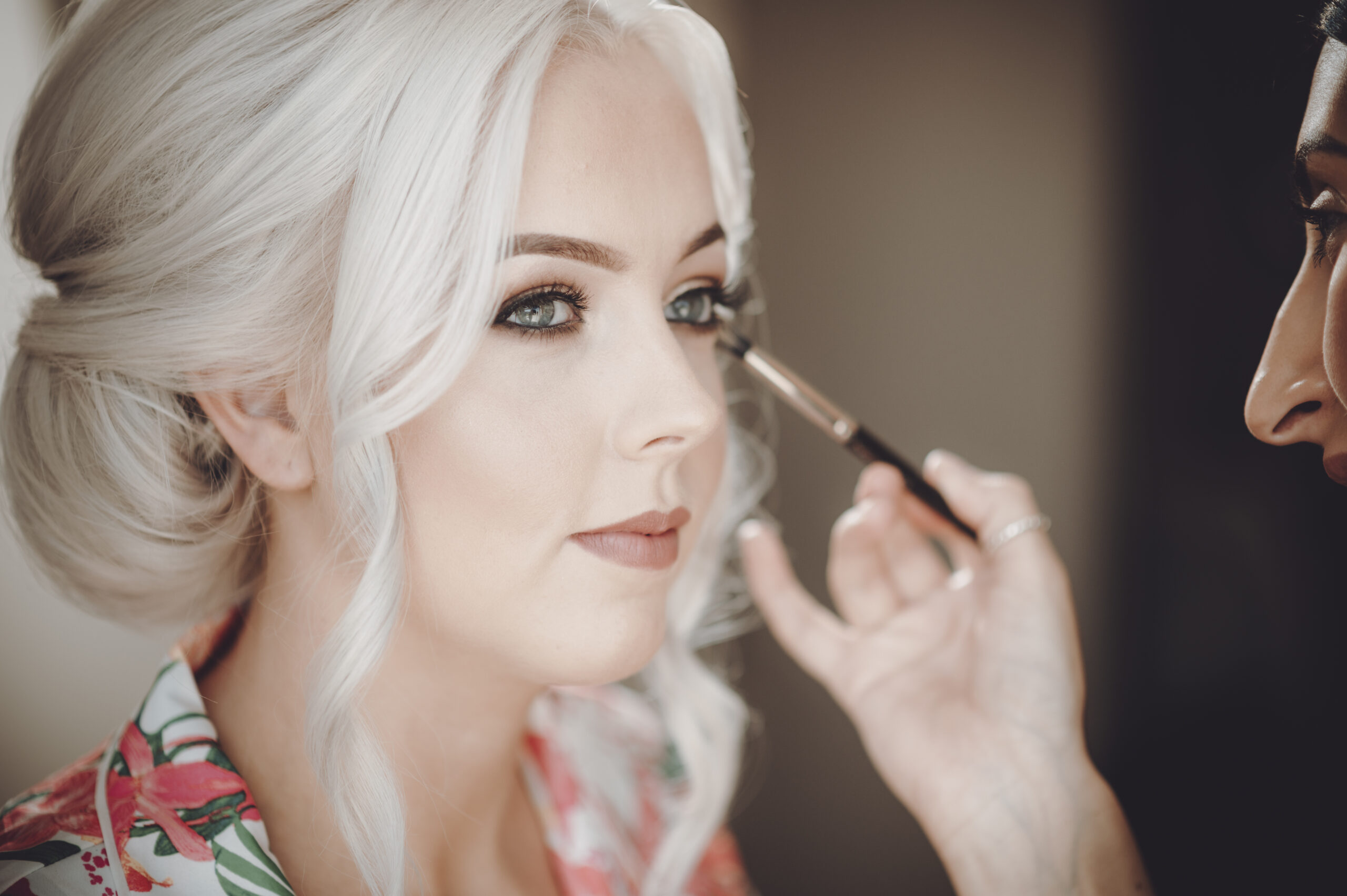 A bride getting her makeup done by a makeup artist. (listing)