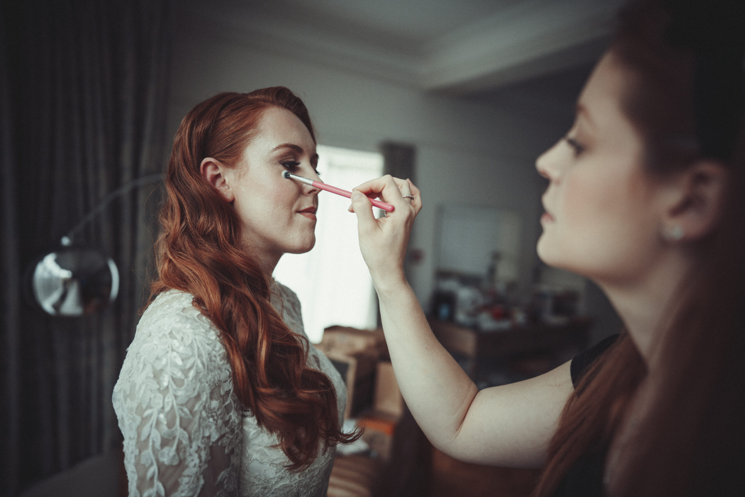 A bride getting her makeup done by a wedding photographer. (listing)