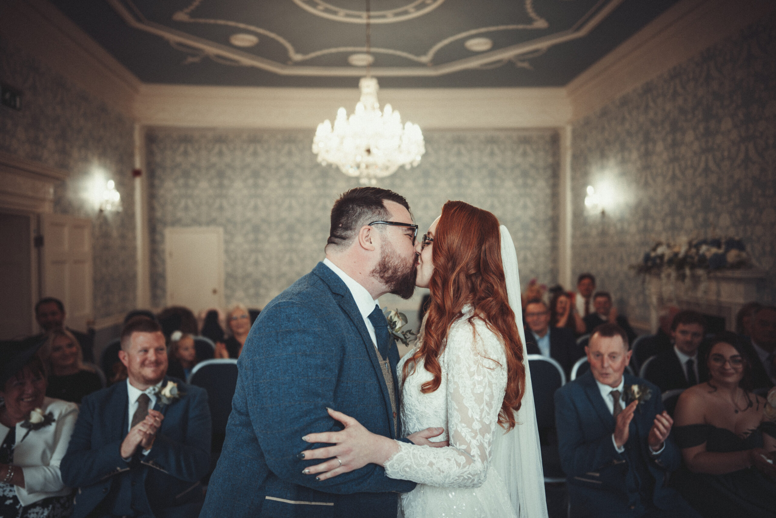 A bride and groom kissing in front of an audience. (listing)