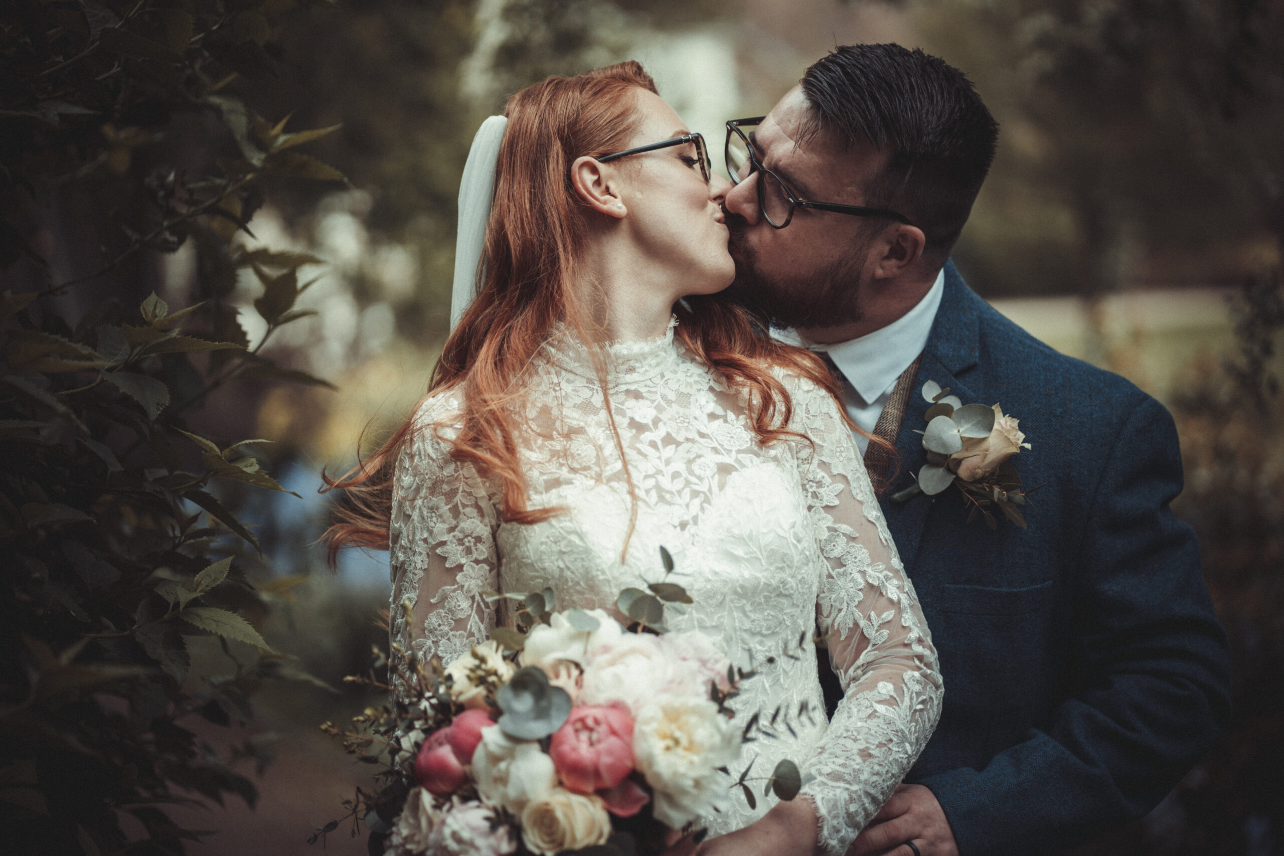 A bride and groom kissing in a garden. (listing)