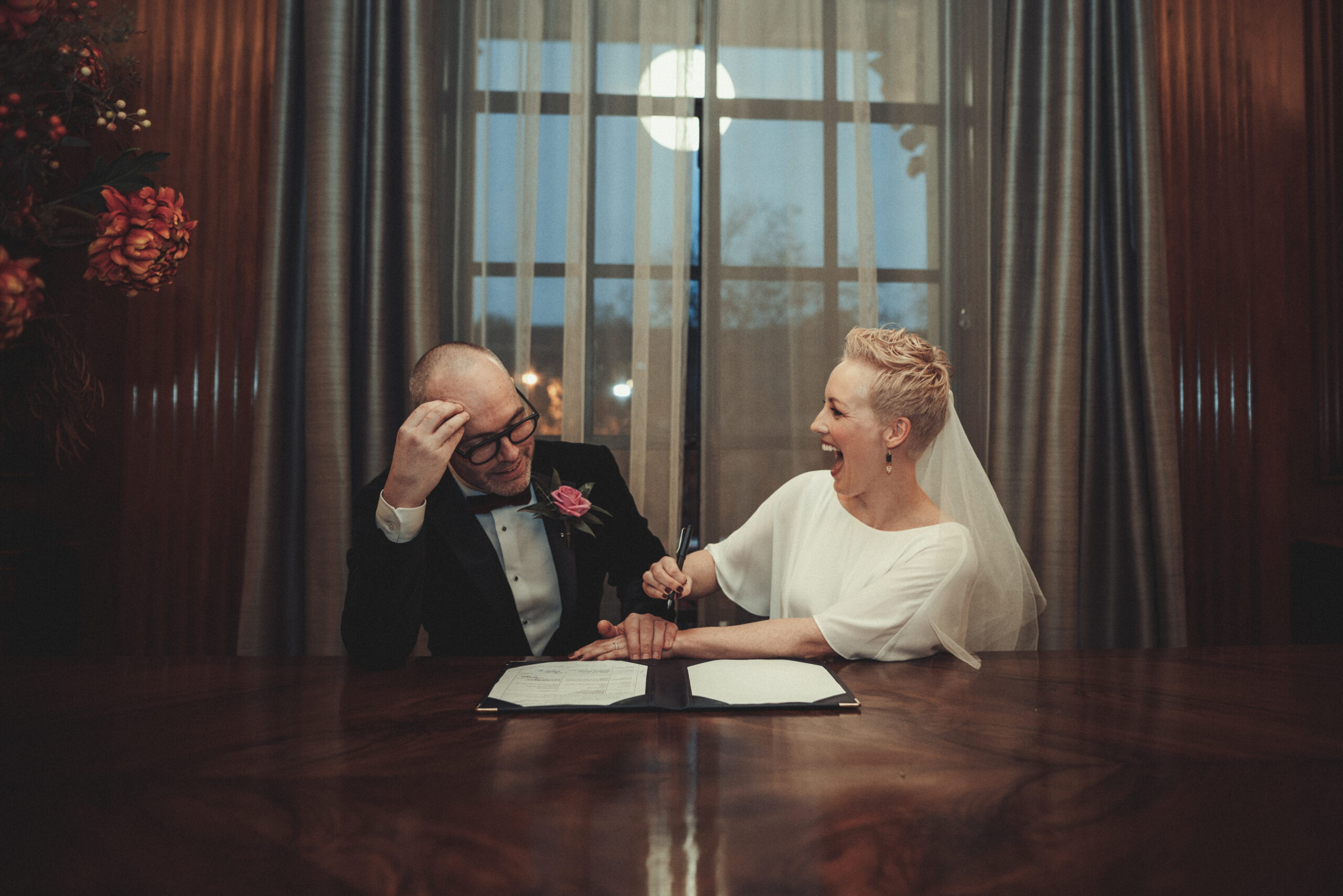 A bride and groom signing their wedding vows at a table. (listing)
