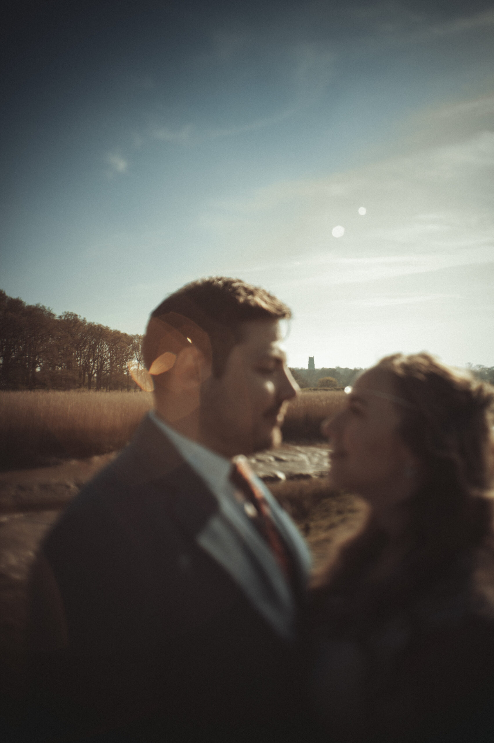 A bride and groom standing in front of a field. (listing)