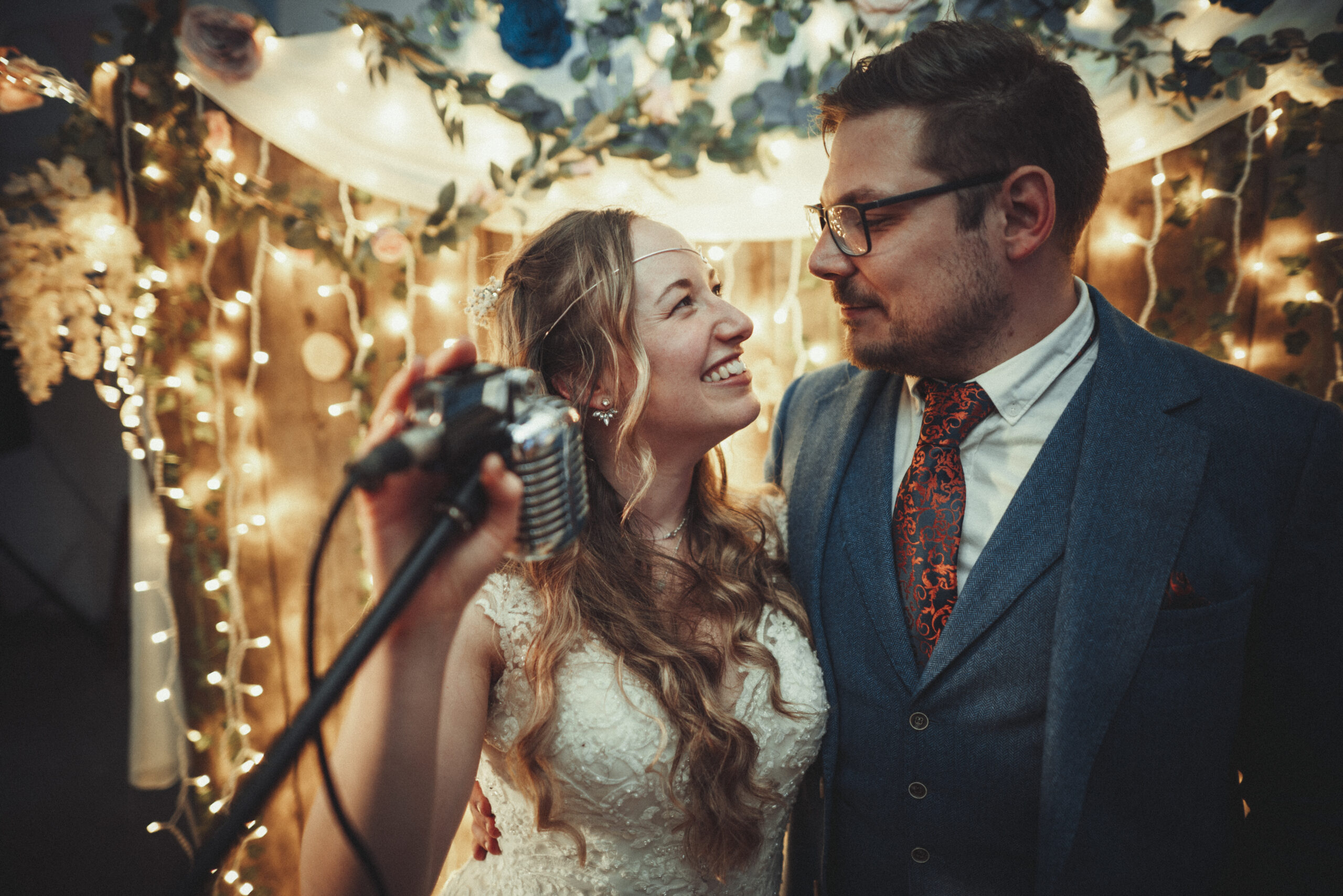 A bride and groom standing in front of a microphone. (listing)