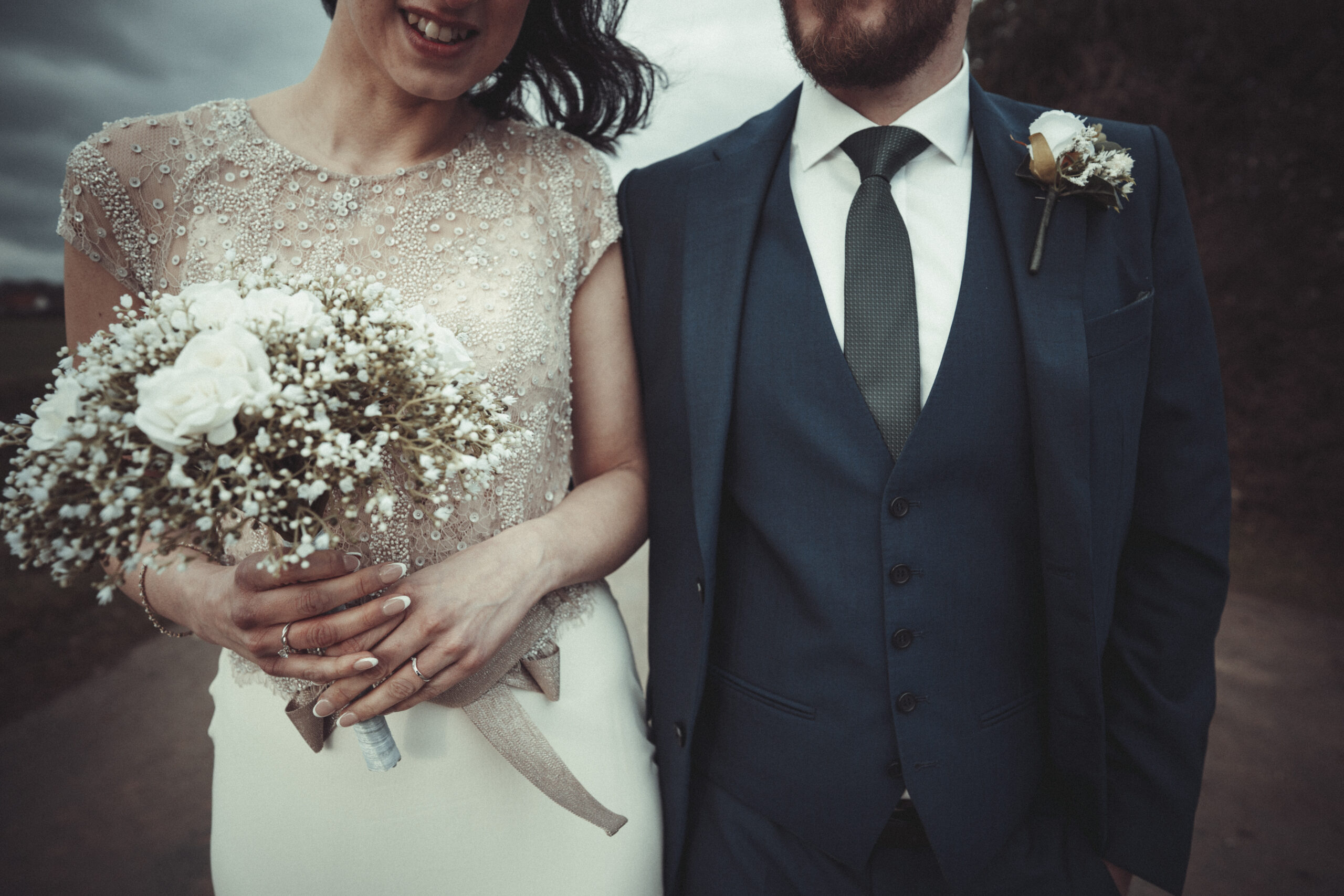 A bride and groom standing next to each other holding a bouquet of baby's breath. (listing)